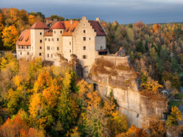 Die Burg Rabenstein im Herbst auf ihrem Felsen umgeben von herbstlich gefärbtem Wald