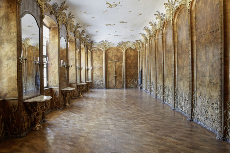 Das Palmenzimmer im Neuen Schloss in Bayreuth, holzgetäfelt, mit goldenen Palmenornamenten an den Wänden.