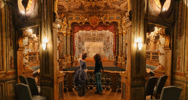Bayreuth_Darstellerin_zeigt_einer_Frau_das_UNESCO_Weltkulturerbe_Markgr_Opernhaus (c) DZT, Julia Nimke