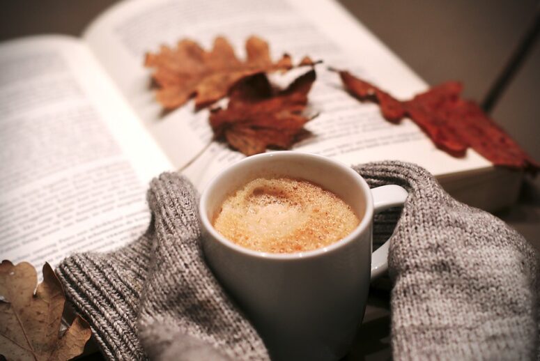 Ein Cappuccino vor einem Buch mit Herbstblatt