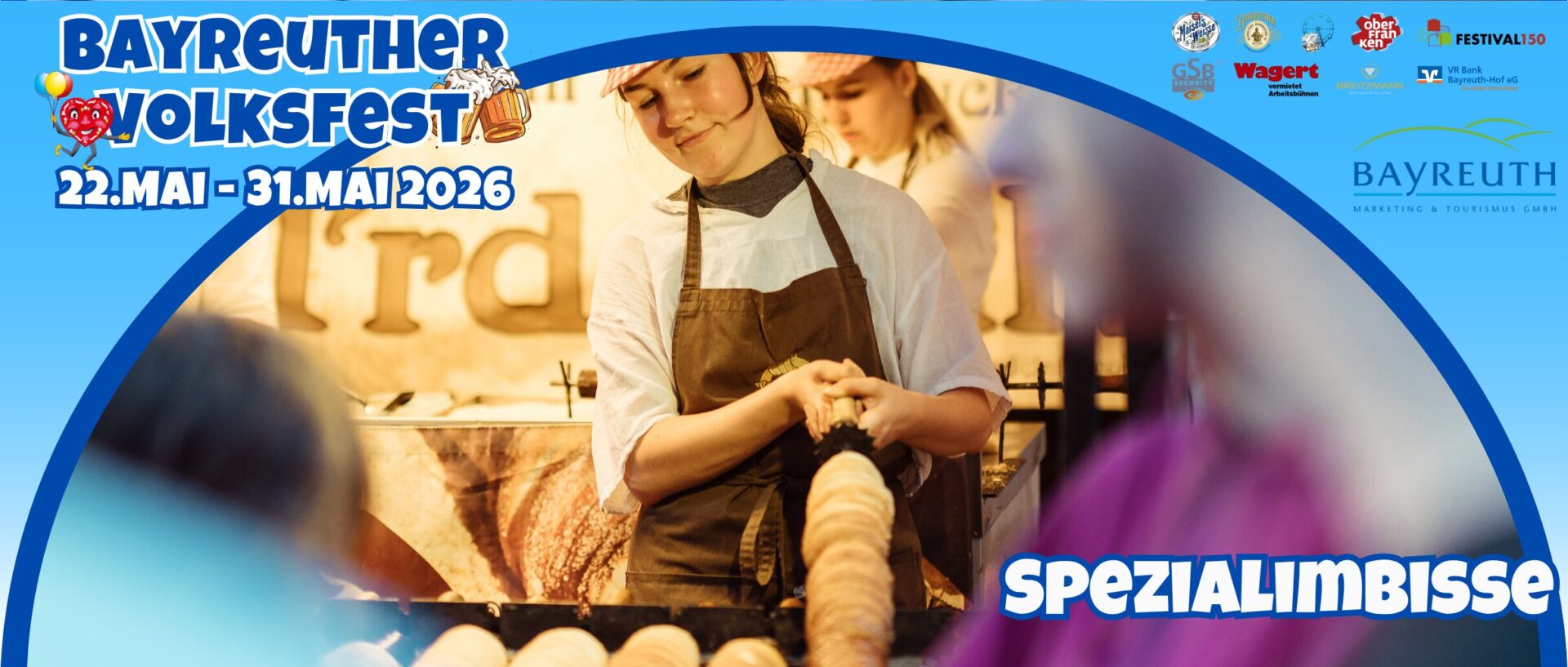 Eine Frau in einer Schürze bereitet an einem Marktstand Lebensmittel zu. Das Banner wirbt für das Bayreuther Volksfest Schausteller vom 22. bis 31. Mai 2026, mit Spezialimbissen und Logos im oberen Bereich.