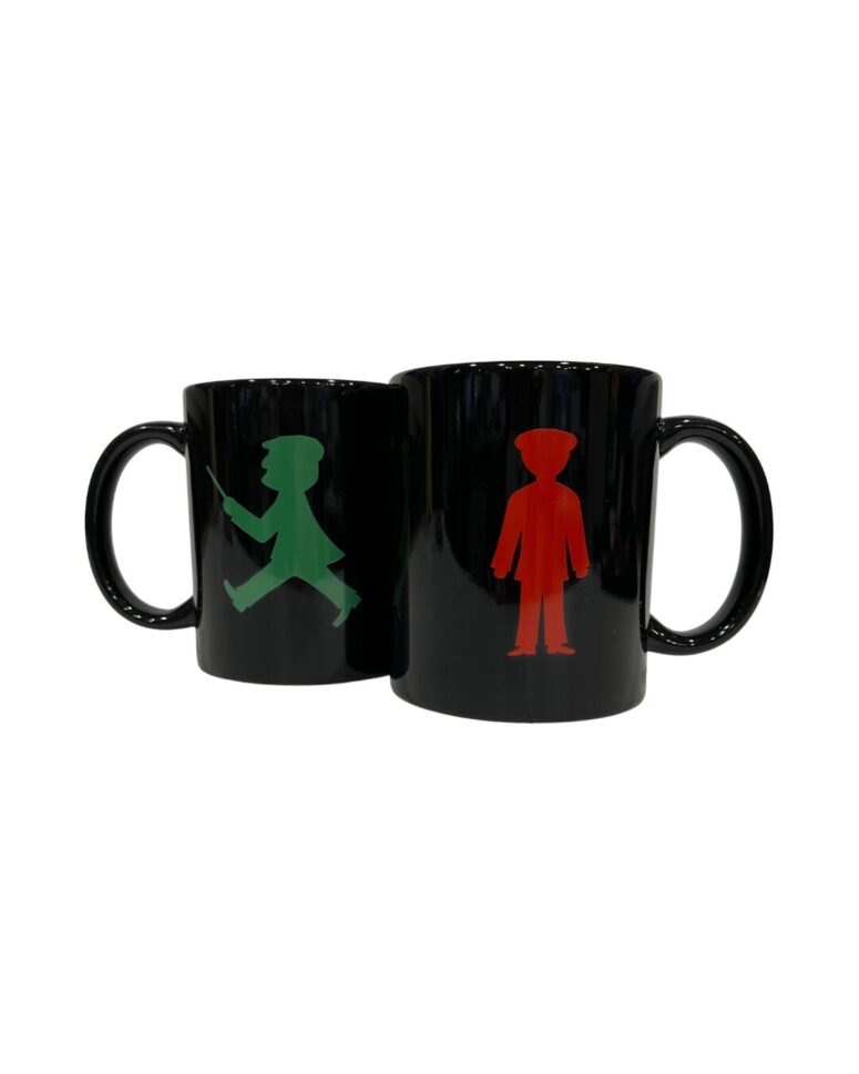 Zwei schwarze Becher mit Henkel aus dem Bayreuth Shop. Die eine zeigt eine grüne Fußgänger-Silhouette, die andere einen roten stehenden Fußgänger, beide vor einem schlichten weißen Hintergrund.