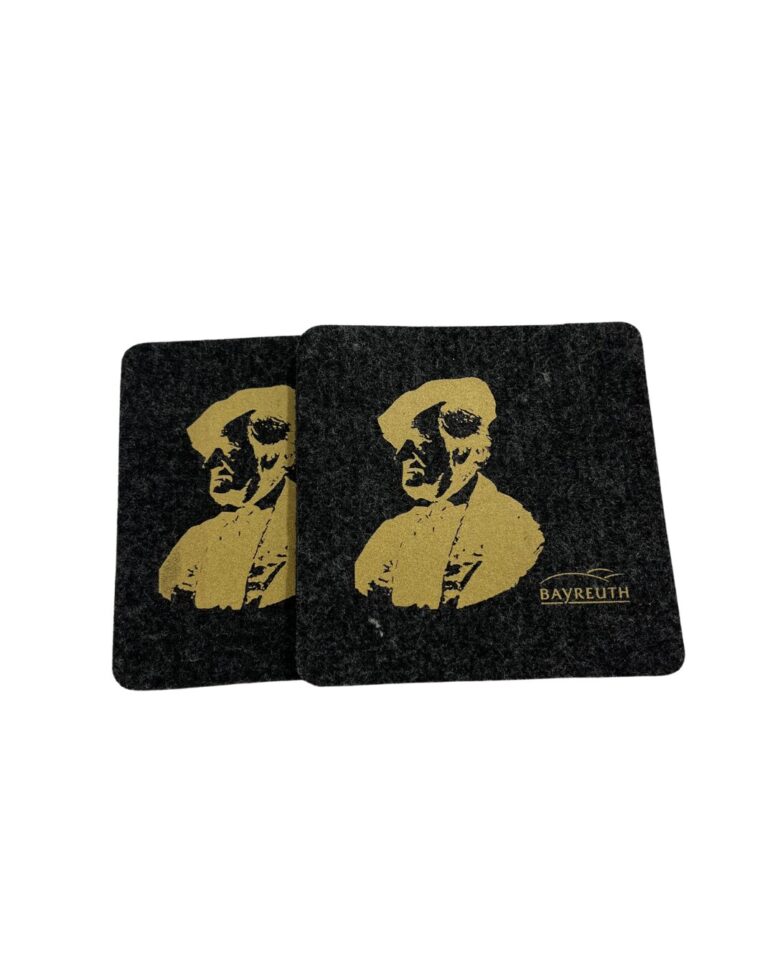 Zwei schwarze quadratische Untersetzer, die im Bayreuth Shop erhältlich sind, zeigen eine goldene Illustration eines Mannes in historischer Kleidung und das Wort BAYREUTH, das elegant auf einen Untersetzer gedruckt ist.