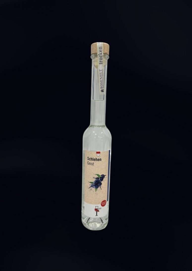 Eine hohe, klare Glasflasche mit Holzkorken, die mit Schlehenbeeren und -blättern beschriftet ist, wird vor einem schlichten schwarzen Hintergrund präsentiert - eine raffinierte Spirituose, die im Bayreuth Shop erhältlich ist.