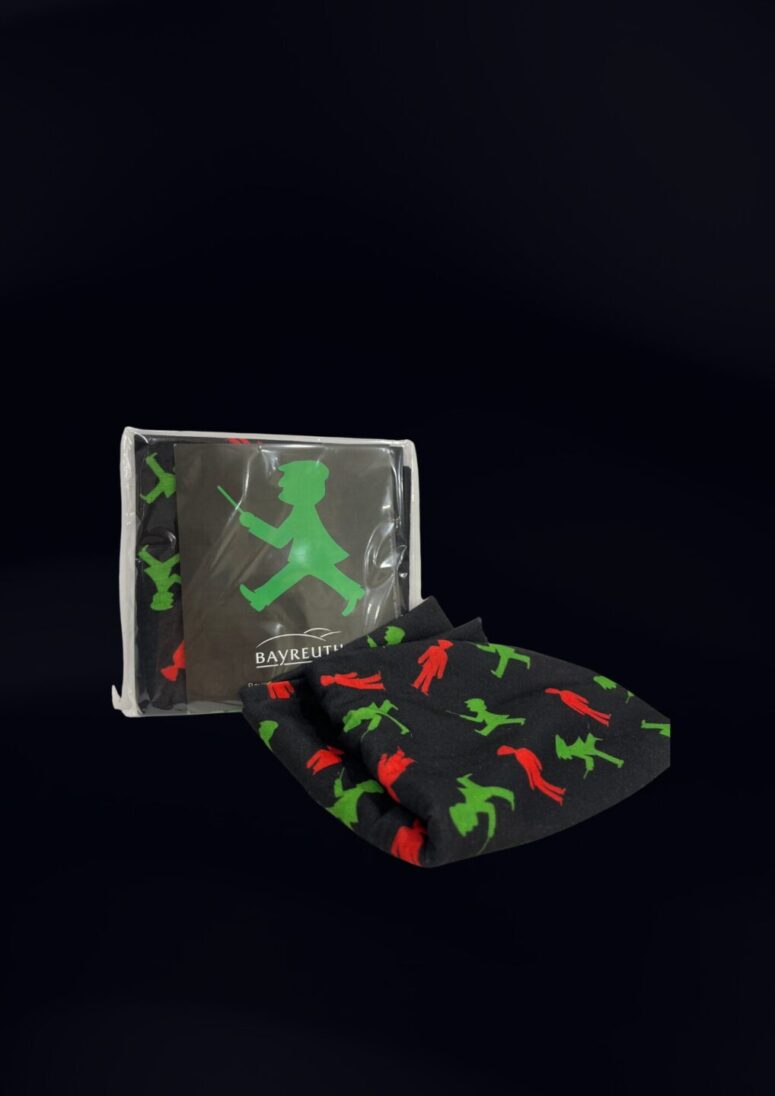 Ein Paar schwarze Socken von Bayreuth Shop mit grünen und roten Fußgängerfiguren, wobei eine Socke ausgestellt und die andere in einer durchsichtigen Plastiktüte vor einem schwarzen Hintergrund verpackt ist.