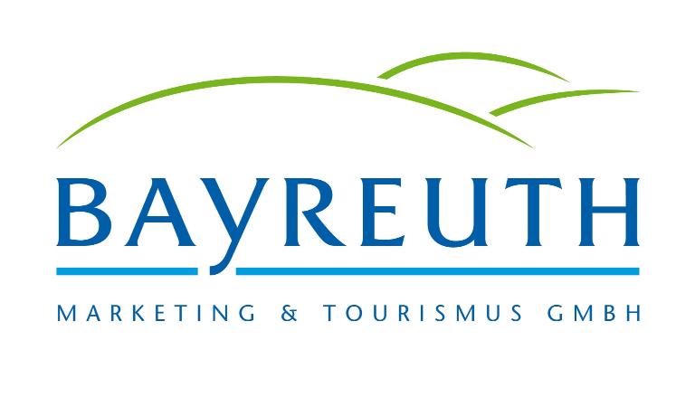 Logo mit dem Wort „BAYREUTH“ in blauen Großbuchstaben, darunter „MARKETING & TOURISMUS GMBH“ und darüber grüne, geschwungene Linien, die an Hügel erinnern und die Unterstützung für „STADTRADELN“ hervorheben.