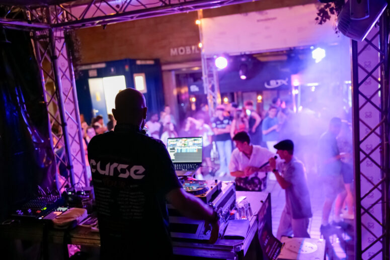 Ein DJ legt nachts auf der Bühne bei buntem Licht und Nebel auf und heizt dem ausgelassenen Publikum ein, das beim Bürgerfest 2026 – einem unvergesslichen Open-Air-Event – tanzt und die Musik genießt.