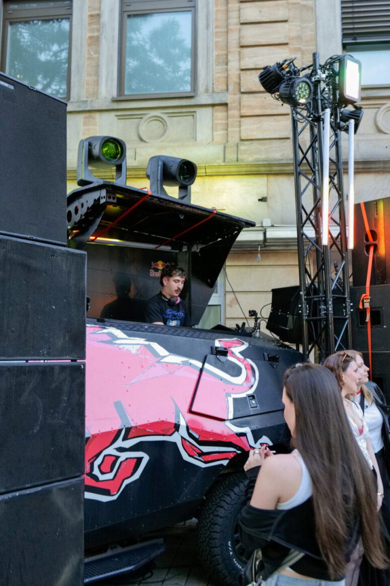 Auf dem Bürgerfest 2026 legt ein DJ auf einer Außenbühne auf, die auf einem großen Fahrzeug mit einem Red-Bull-Logo aufgebaut ist und von Lautsprechern und Scheinwerfern umgeben ist. Vor der Bühne stehen mehrere Menschen und verfolgen die lebhafte Show.