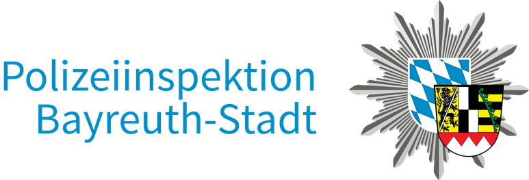 Blauer Schriftzug „Polizeiinspektion Bayreuth-Stadt“ neben einem Wappenabzeichen mit bayerischen blauen und weißen Rauten, schwarzen und goldenen Löwen sowie einem roten Feld, alles vor einem silbernen Sternstrahlen-Emblem – ein offizielles Erscheinungsbild, das bei kommunalen Veranstaltungen wie der TOGGO-Tour zu sehen war.