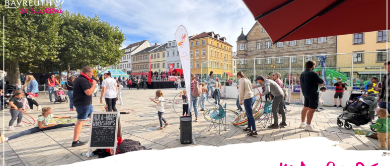 Teilnehmer eines Hula-Hoop-Workshops bei einem Festival auf einem Stadtplatz im Rahmen der Bayreuther Festspiele unter freiem Himmel.