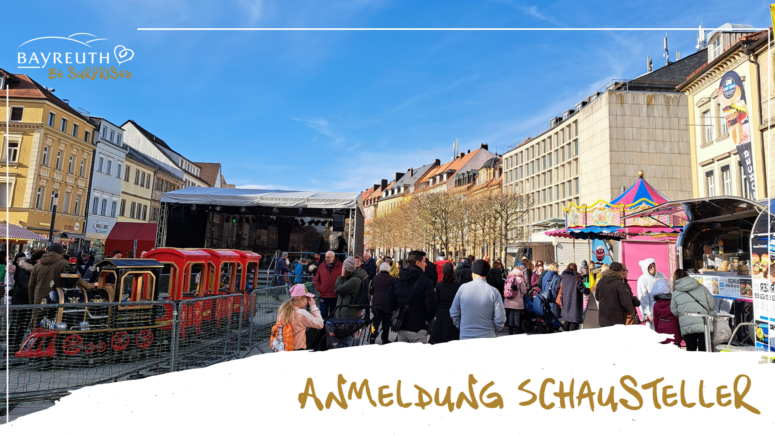 Bei einem Straßenfest in Bayreuth versammelt sich eine Menschenmenge, um einen kleinen schienenlosen Zug und ein buntes Karussell zu bewundern, die im Rahmen des Faschingsumzugs mit lokalen Vereinen zu sehen sind.