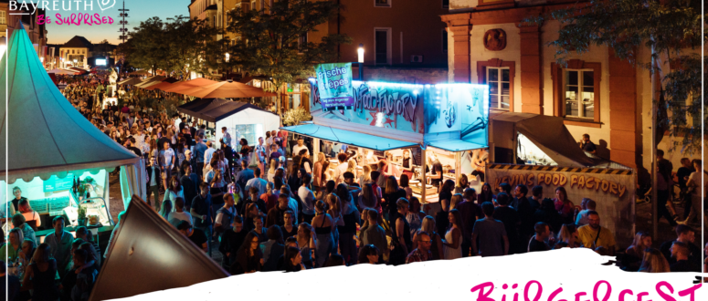 Ein gut besuchtes Straßenfest im Freien in der Abenddämmerung, mit von Leuchtreklamen beleuchteten Imbissständen und dem Schriftzug BÜRGERFEST in der Ecke.