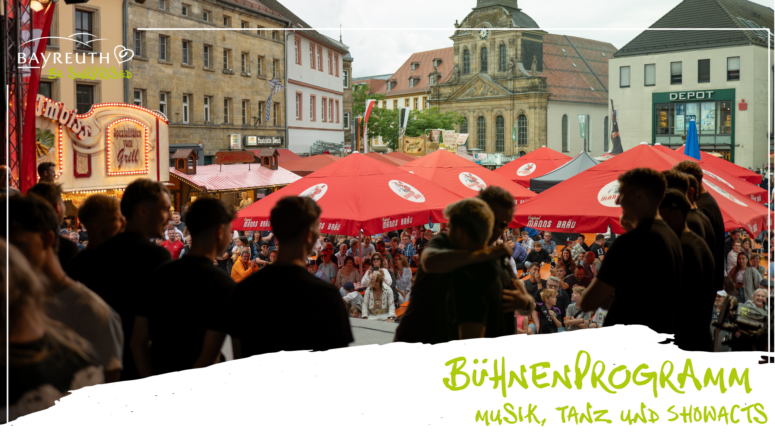 Eine Menschenmenge aus Mitgliedern lokaler Vereine verfolgt auf einer Freiluftbühne bei einem Fest in Bayreuth eine Darbietung im Rahmen eines Faschingsumzugs, umgeben von roten Biermarkisen und Marktständen.