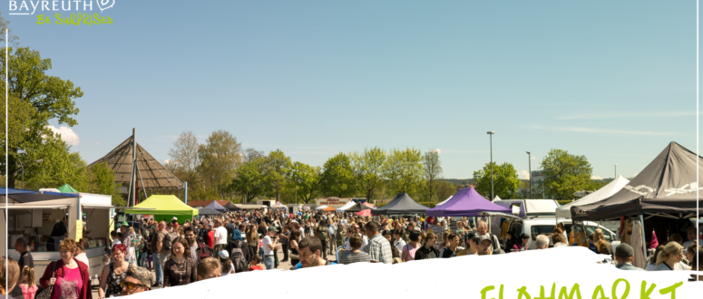 Ein belebter Flohmarkt unter freiem Himmel in Bayreuth, auf dem an einem sonnigen Tag viele Menschen an den Ständen unter verschiedenen Zelten stöbern.