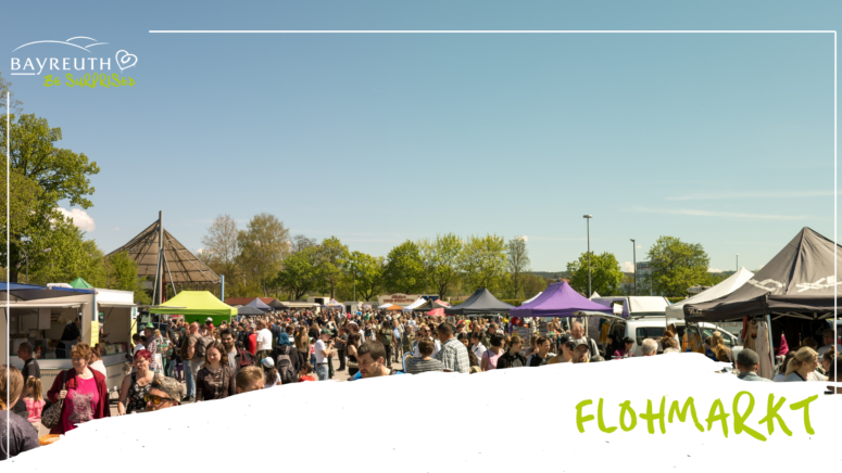 Ein belebter Flohmarkt unter freiem Himmel in Bayreuth, auf dem an einem sonnigen Tag viele Menschen an den Ständen unter verschiedenen Zelten stöbern.