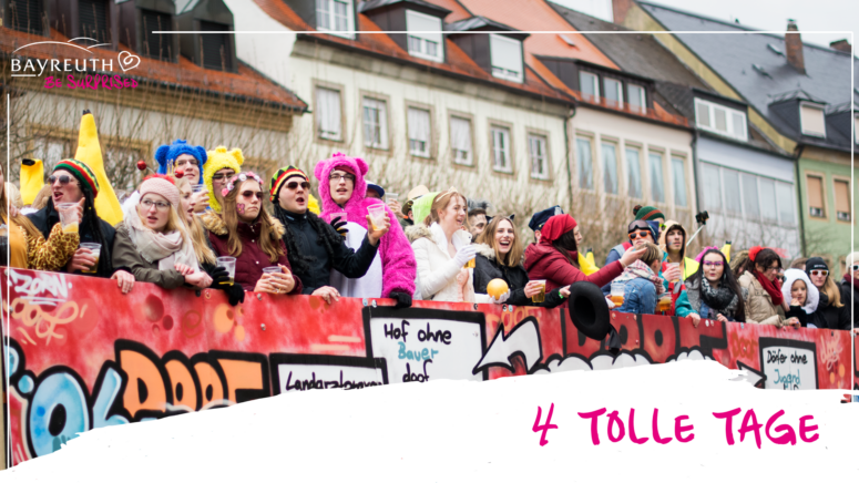 Eine Gruppe von Menschen in Kostümen und mit Hüten steht auf einem roten, mit Graffiti verzierten Festwagen, hält Getränke in den Händen und lächelt; unten rechts ist der Schriftzug 4 TOLLE TAGE zu sehen.
