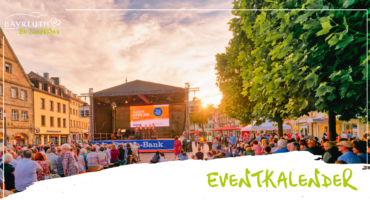 Eine Open-Air-Konzertbühne auf einem Stadtplatz mit sitzendem Publikum und einer Leinwand, auf der Klassik Open Air 2024 zu sehen ist.